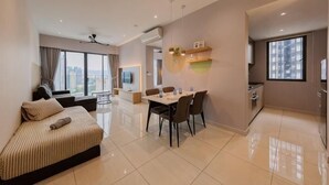 A modern living room with a sofa, dining table, chairs, and a large window. - Datum Jelatek Residence by FEEL HOME (Ampang)