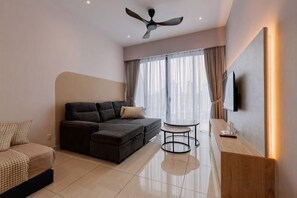 Una sala de estar moderna con un sofá seccional, una mesita redonda y un ventilador de techo.
