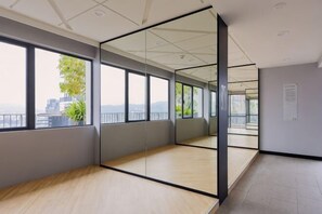 Una habitación amplia con ventanas grandes, piso de madera y un panel de vidrio.
