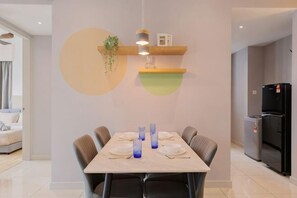 Un comedor con una mesa preparada para seis personas, un refrigerador y una planta en un estante.