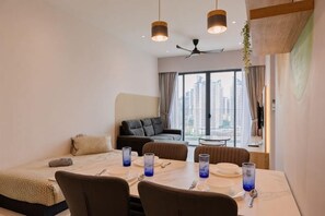 Una habitación de hotel moderna con zona de comedor, sofá y un amplio ventanal con vistas a la ciudad.