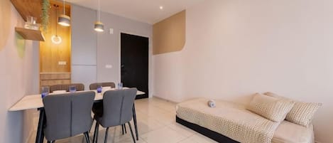 A modern living space with a dining area, a sofa, and a kitchen.