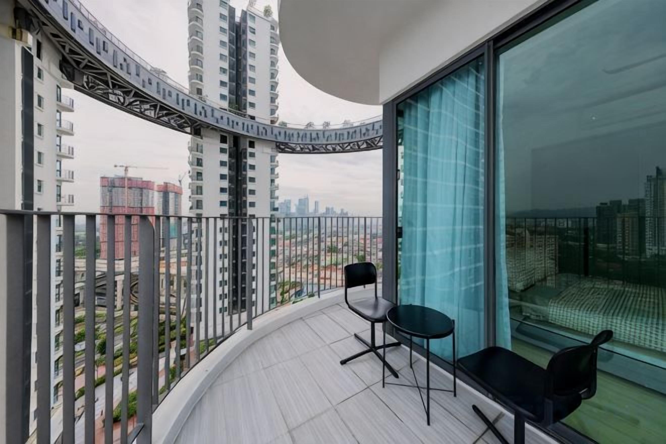 A balcony with a curved railing, a chair, and a table.