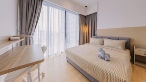 A modern hotel room with a large bed, a desk, and a view of the city. - Datum Jelatek Residence by FEEL HOME (Ampang)