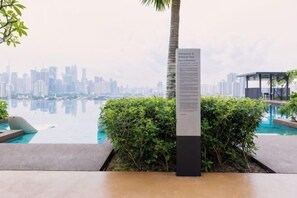 Zona junto a la piscina con vistas al horizonte de la ciudad, una palmera y un cartel.