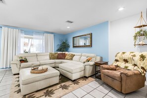 A living room with a sectional sofa, a chaise lounge, a coffee table, a side table, and a hanging plant.