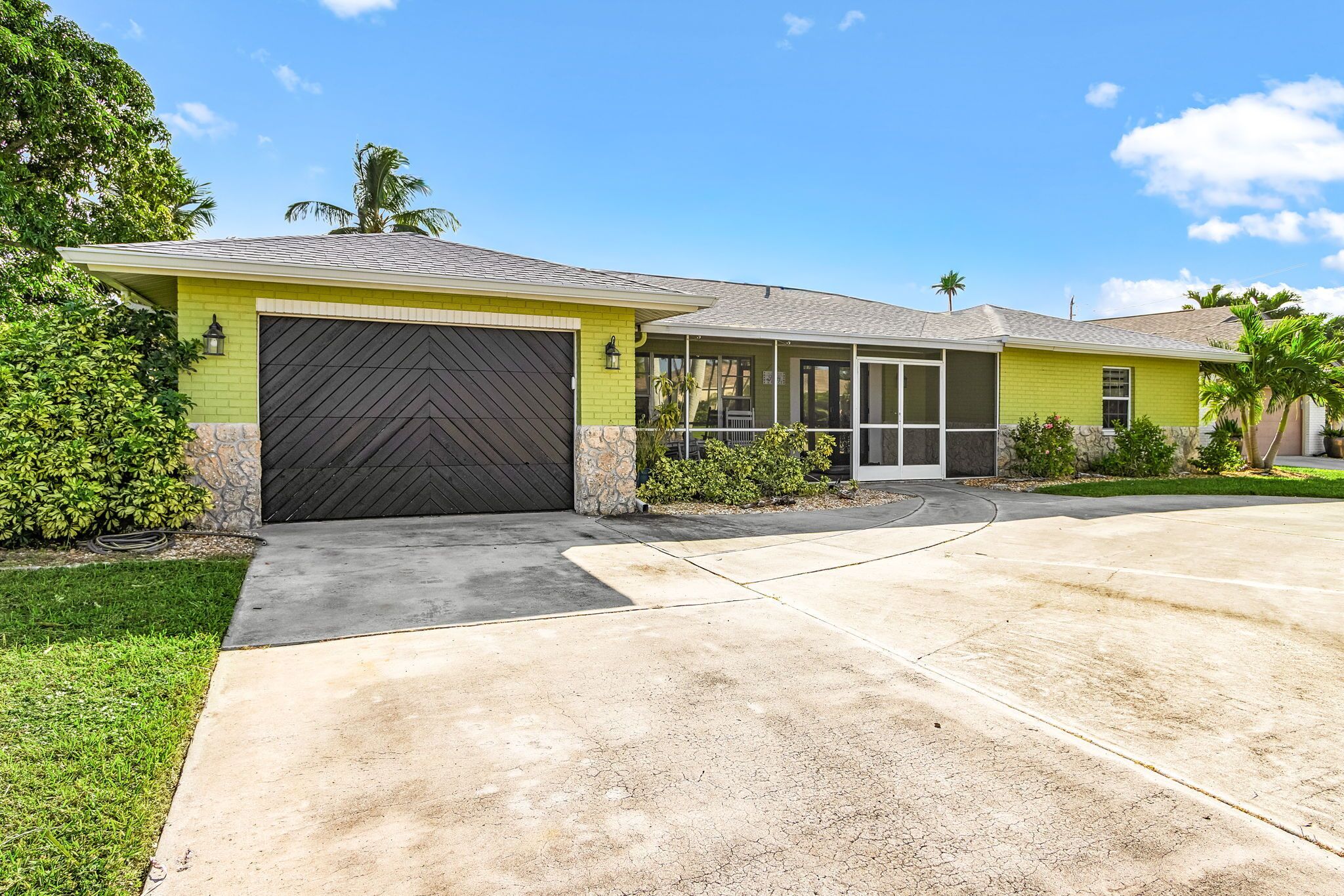 A residential house with a garage, a covered porch, and a well-maintained lawn.
