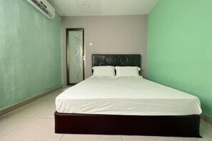 A bedroom with a bed, a door, and a wall-mounted air conditioner.