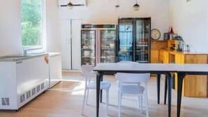 A modern kitchen with white appliances, a wooden ceiling, and a large window. - Evelyaa Guest House (Fulidhoo)