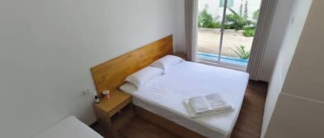 A single bed with a wooden headboard in a room with a window.