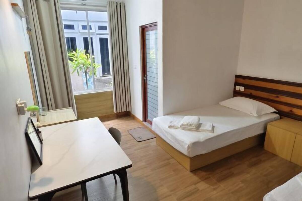 Una camera d'albergo con un letto, una scrivania, una sedia e una finestra con tende.