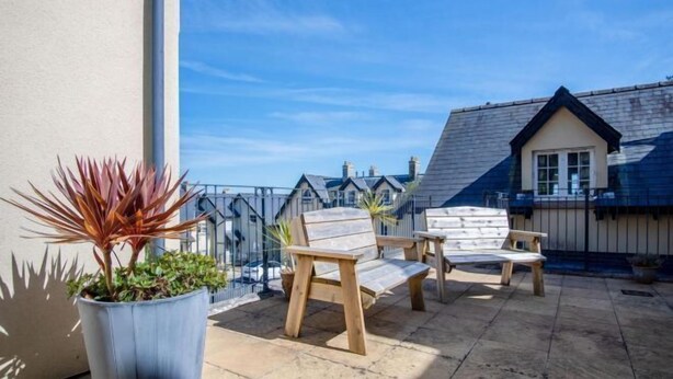 A balcony with two wooden chairs and a potted plant. - 29 Rhodewood House - 2 Bedroom - Saundersfoot (Saundersfoot)