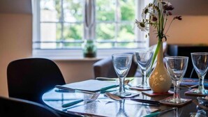 A dining table set with clear glassware and a vase with flowers, positioned near a window with a view of greenery. - 29 Rhodewood House - 2 Bedroom - Saundersfoot (Saundersfoot)