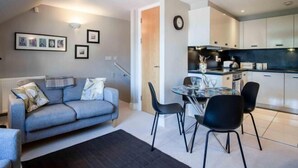 A modern living room with a grey sofa, black chairs, and a dining table. - 29 Rhodewood House - 2 Bedroom - Saundersfoot (Saundersfoot)