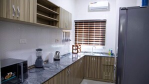Cocina compacta con armarios de madera, un microondas, una licuadora y un refrigerador.