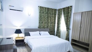 Una habitación de hotel moderna con cama, mesita de noche, lámpara y armario.
