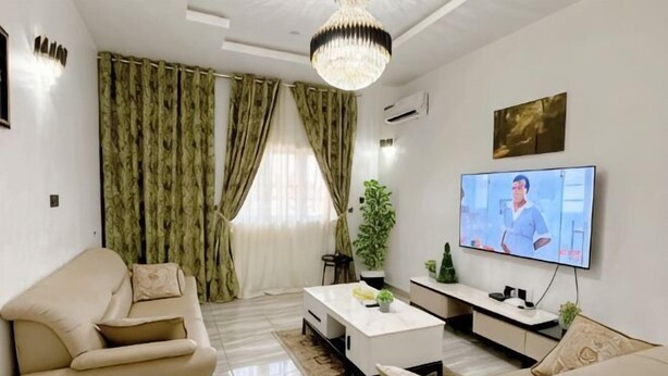 Una sala de estar con un sofá, una mesa de centro, un televisor y cortinas.