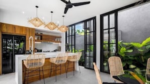 Una cocina moderna con una isla central, taburetes de bar e iluminación colgante.