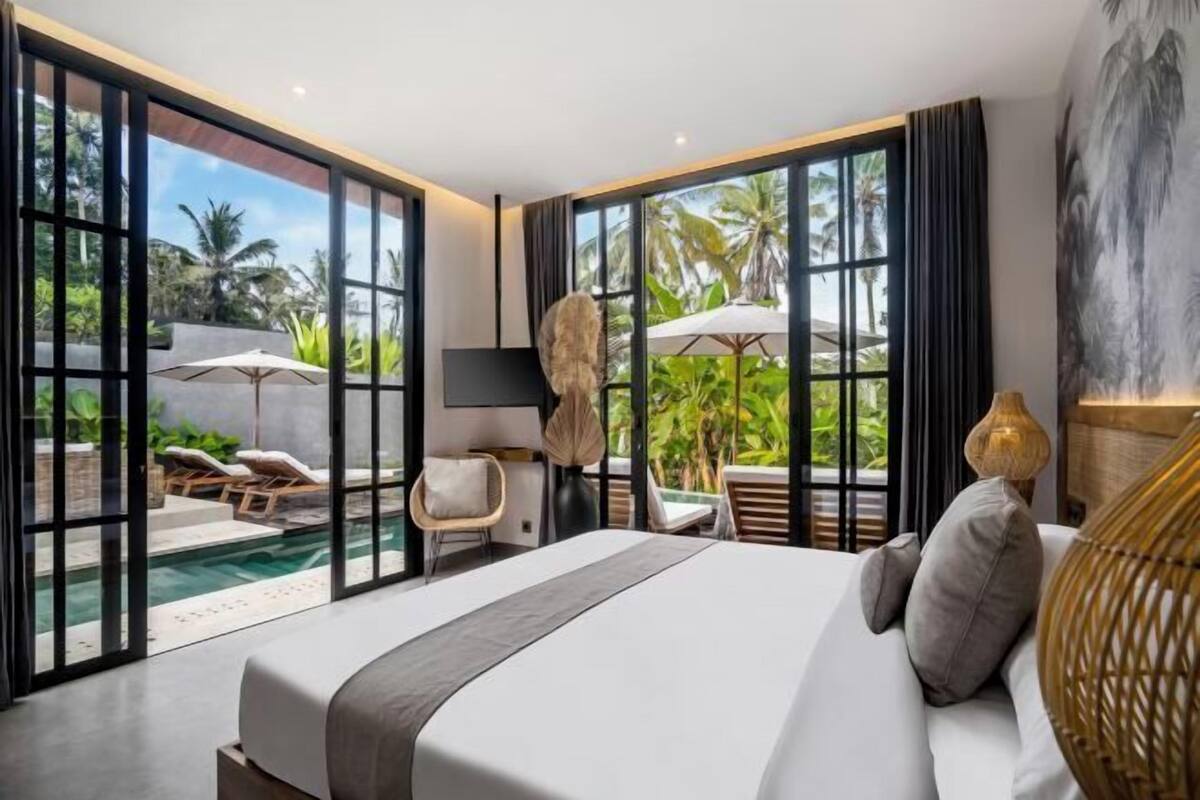 Camera d'albergo moderna con un grande letto, vista su una piscina e un balcone con mobili da esterno.