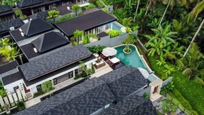Un moderno resort con varias construcciones, una piscina y abundante vegetación tropical.