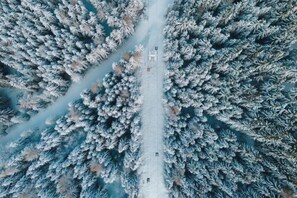 An aerial view of a snow-covered forest with a clear path leading through it. - Luxescape-No 2306-Traumaussicht-Ski & Wandergebiet-Paragleiten-Langlauf-Parkplatz (Treffen bei Villach)