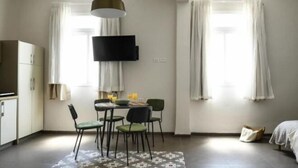 A modern room with a dining area, a bed, and a TV mounted on the wall. - The Printhouse Downtown Studio 10 (Haifa)