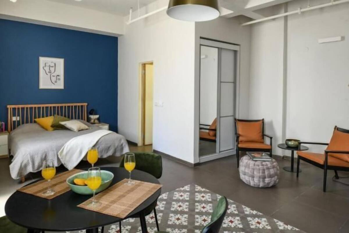 Une chambre d’hôtel moderne comprenant un lit, une table à manger avec des chaises, un canapé et une petite table ronde sur laquelle se trouvent un bol et des verres.