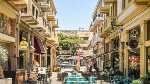 A narrow street lined with cafes and shops, featuring outdoor seating and a clear view of the street. - The Printhouse Downtown Studio 10 (Haifa)