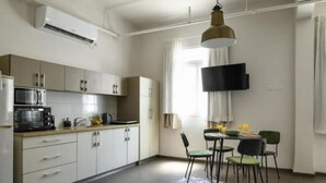 A modern kitchen with a microwave, stove, and cabinets. There is a dining area with a table and chairs. - The Printhouse Downtown Studio 10 (Haifa)