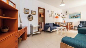 Ein Wohnzimmer mit einer Couch, einem Couchtisch, einem Esstisch mit Stühlen, einer Holzkommode und einer Wand mit gerahmten Bildern.