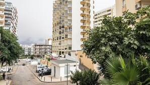 Ein mehrstöckiges Wohnhaus mit Balkonen, einem Parkplatz und umliegender Bepflanzung.