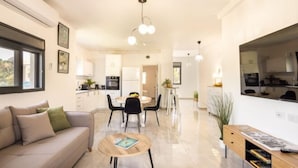 Un salon moderne comprenant un canapé, une table basse, un coin repas, une cuisine et une grande fenêtre.