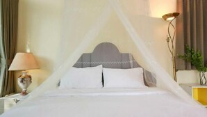 A bed with a canopy, a nightstand with a lamp, and a wall-mounted lamp. - Little Tree House(3 bedrooms) (Pak Chong)