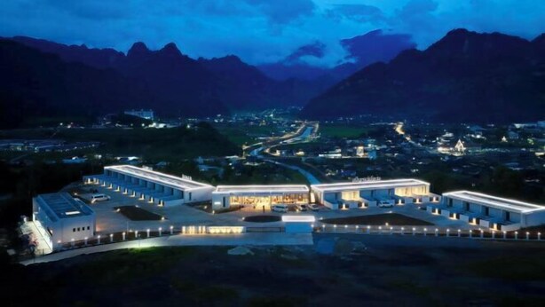 A modern hotel with a central courtyard, surrounded by mountains.