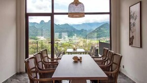 A dining area with a table and chairs, large windows with a mountain view, and a hanging light fixture.