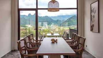 A dining area with a table and chairs, large windows with a mountain view, and a hanging light fixture.