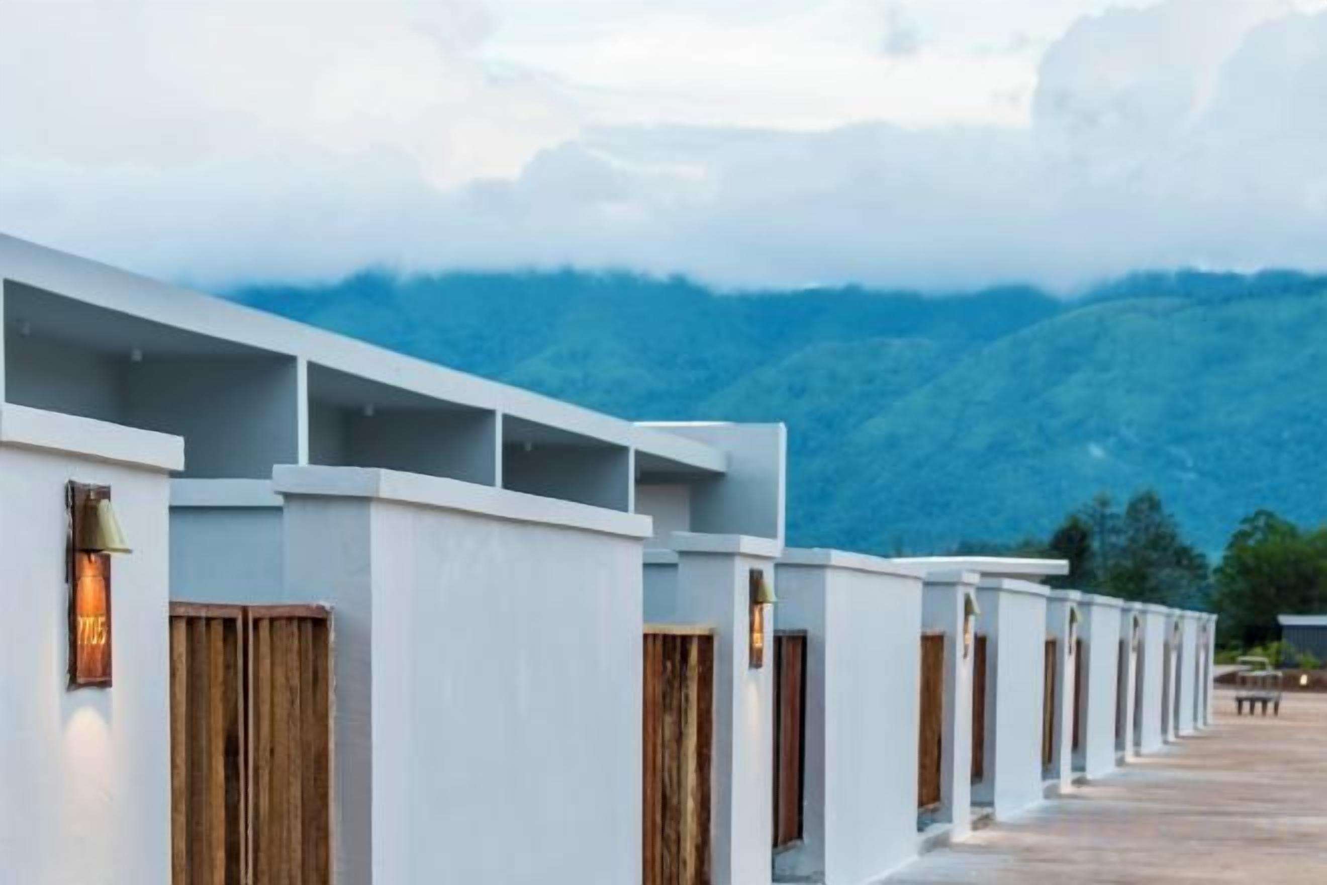 Une rangée de bâtiments blancs aux portes en bois, se dressant sur fond de montagnes.