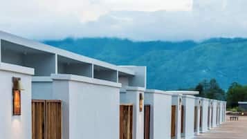 Une rangée de bâtiments blancs aux portes en bois, se dressant sur fond de montagnes.