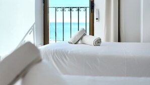 Habitación de hotel con cama, vista al mar y barandilla de balcón.