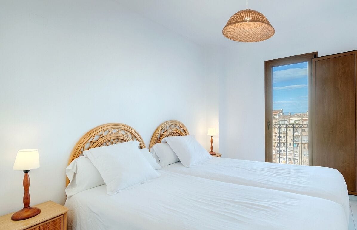 Une chambre avec deux lits, une grande fenêtre et une vue sur les immeubles.
