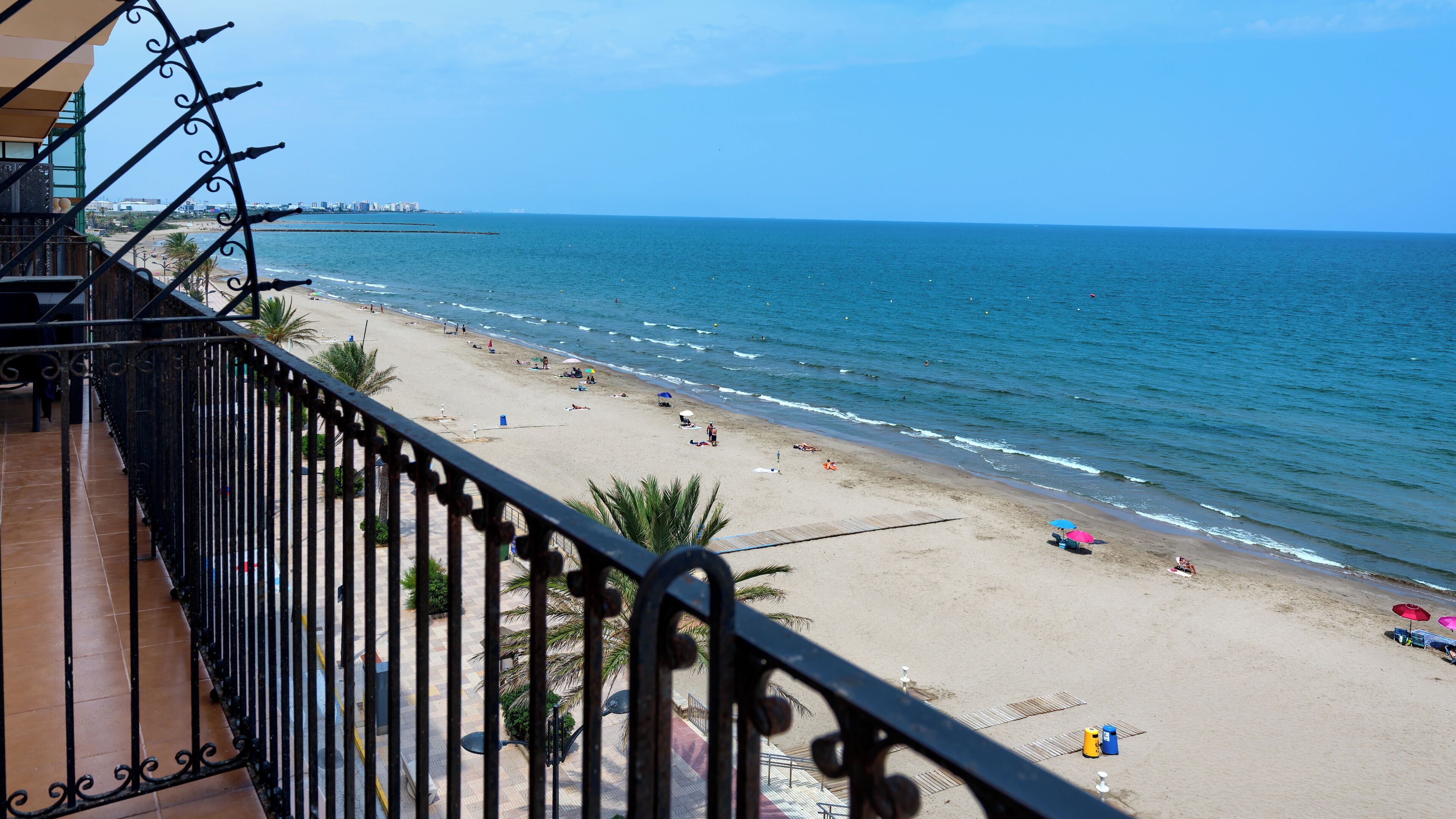 Une vue sur la plage depuis un balcon doté d’une balustrade, avec une plage de sable et l’océan en toile de fond.