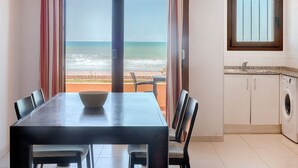 Comedor con vista a la playa, lavadora y ventana con rejas.