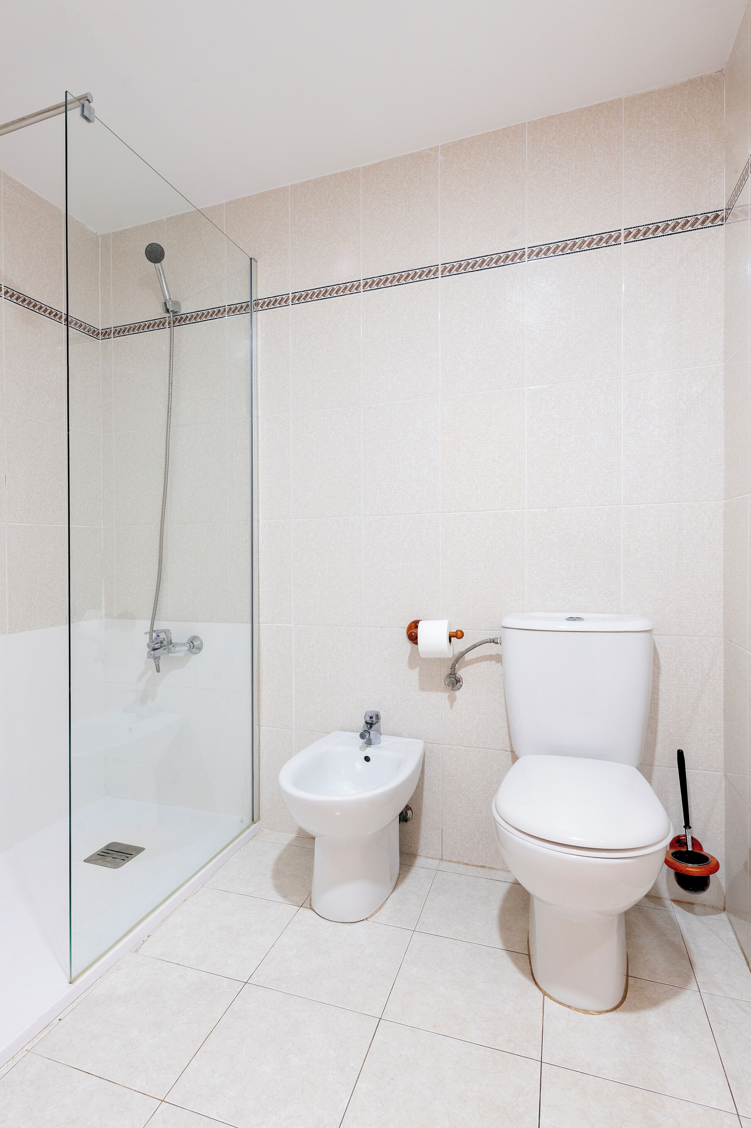 Une salle de bain avec une douche à parois de verre, un bidet et des toilettes.