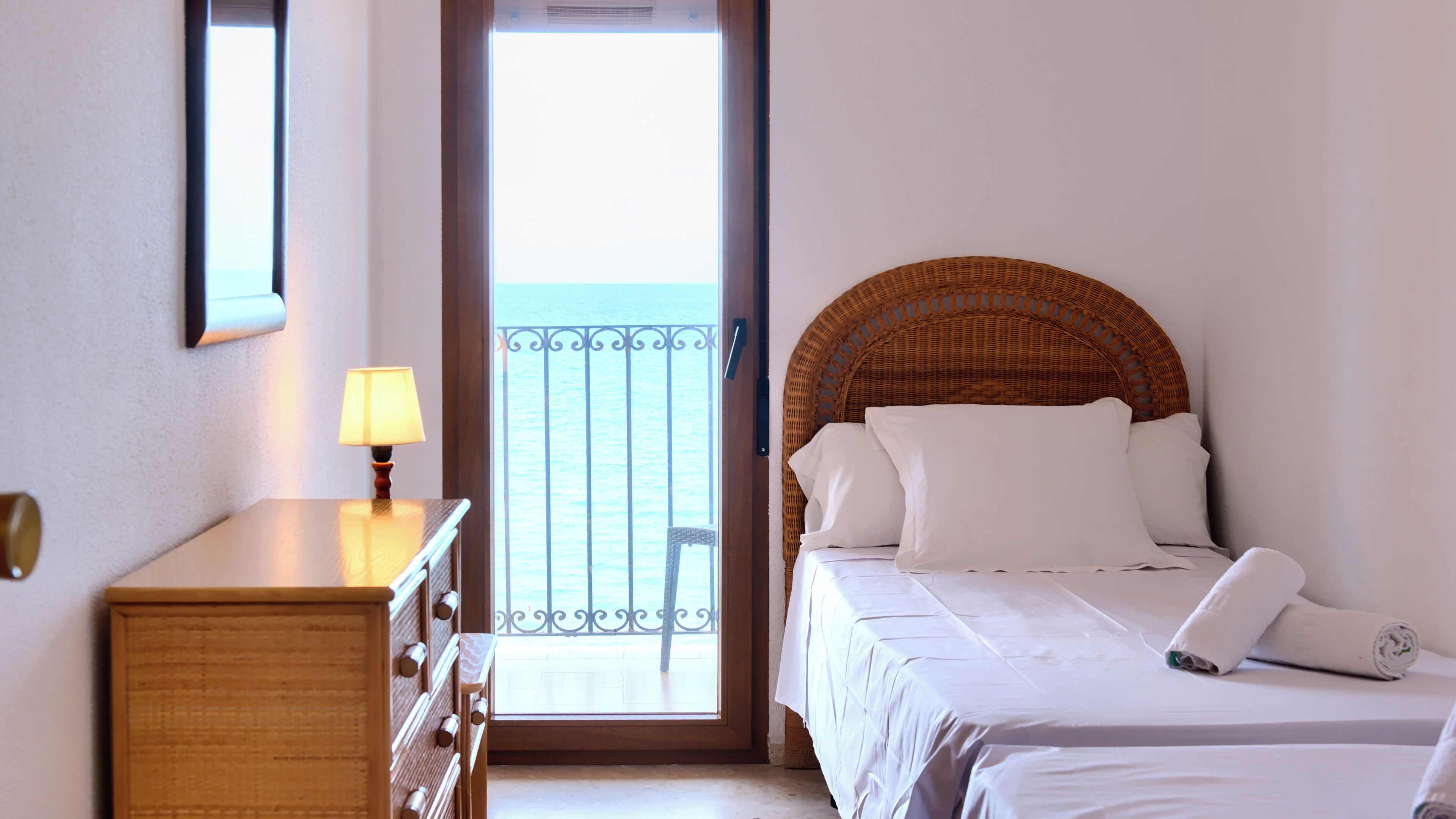 Een hotelkamer met een bed, een dressoir, een lamp en een balkon met een leuning.