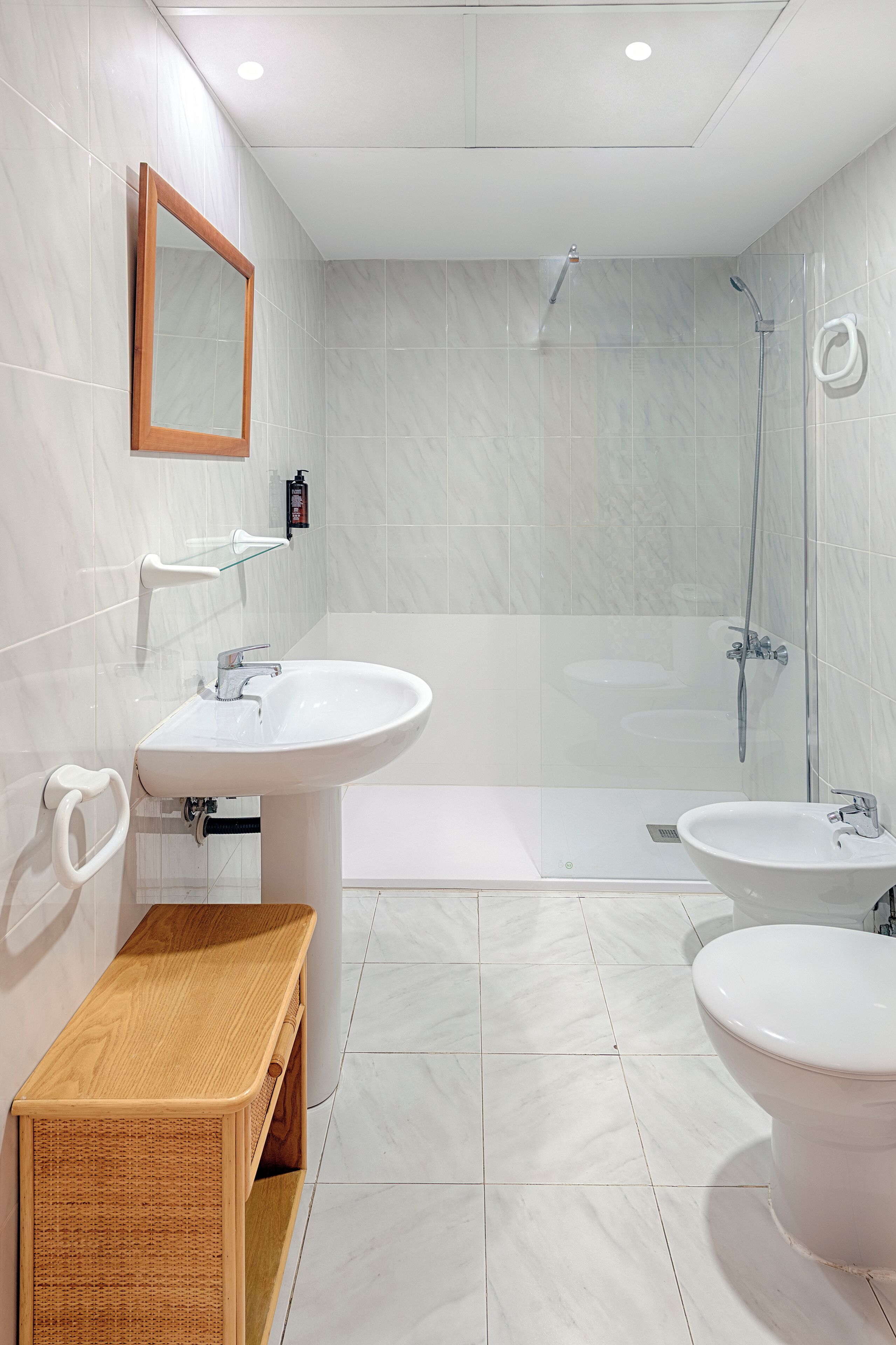 Un baño moderno con bañera, dos lavabos, un espejo y un banco de madera.
