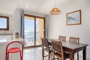 A dining area with a wooden table and chairs, a red chair, a hanging light fixture, and a painting on the wall. - Sea You Aptos Valencia Port Saplaya  (Port Saplaya)