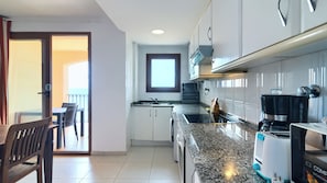 A modern kitchen with white cabinets, a granite countertop, and a built-in oven. - Sea You Aptos Valencia Port Saplaya  (Port Saplaya)