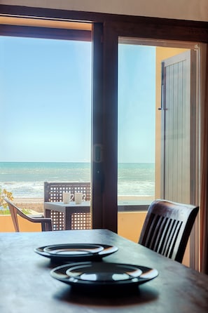A table with plates and a chair, a view of the beach and ocean through an open door. - Sea You Aptos Valencia Port Saplaya  (Port Saplaya)