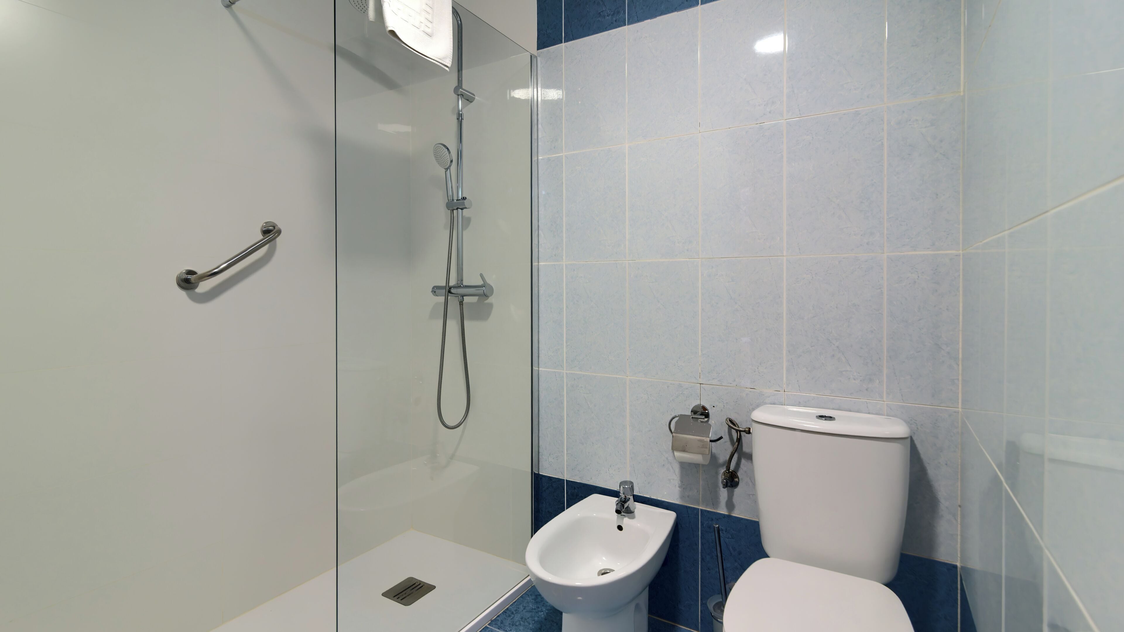 Ein modernes Badezimmer mit Duschkabine aus Glas, einem Bidet und einer Toilette.
