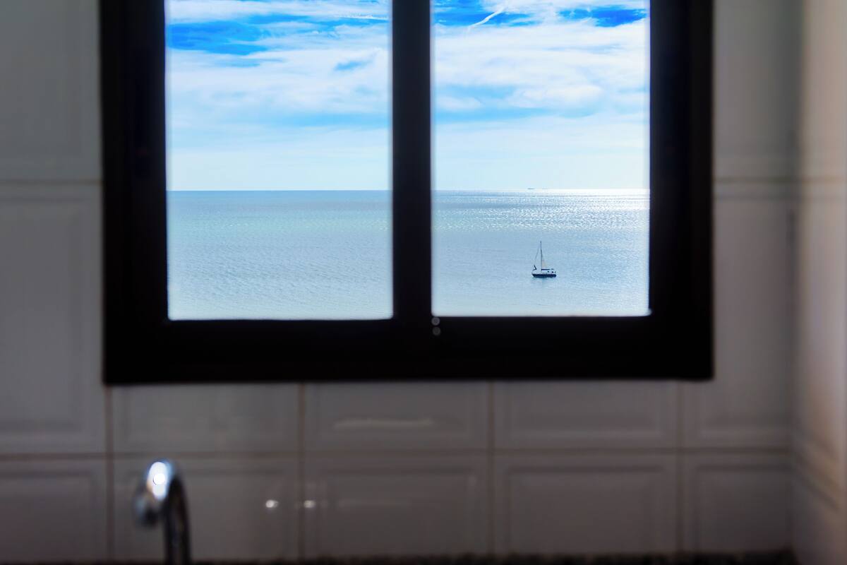 Una finestra amb vista al mar i un veler.